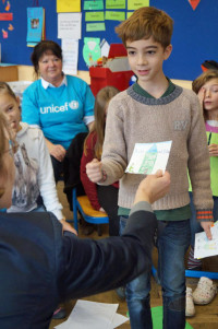 Ein Schüler überreicht Ulrike Bahr die postkartengroßen Bilder zum Thema Kinderrechte.